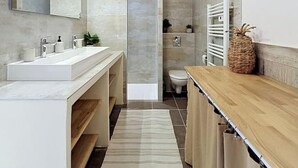 A modern bathroom with a large mirror, two sinks, a shower, and a wooden vanity. - Apartment with terrace cap d'ail - near Monaco and Beaches (Cap-d`Ail)