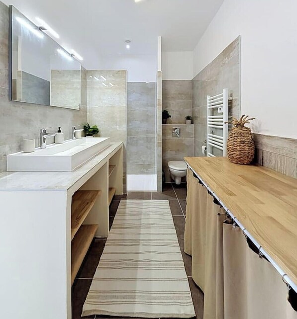 A modern bathroom with a large mirror, two sinks, a shower, and a wooden vanity. - Apartment with terrace cap d'ail - near Monaco and Beaches (Cap-d`Ail)