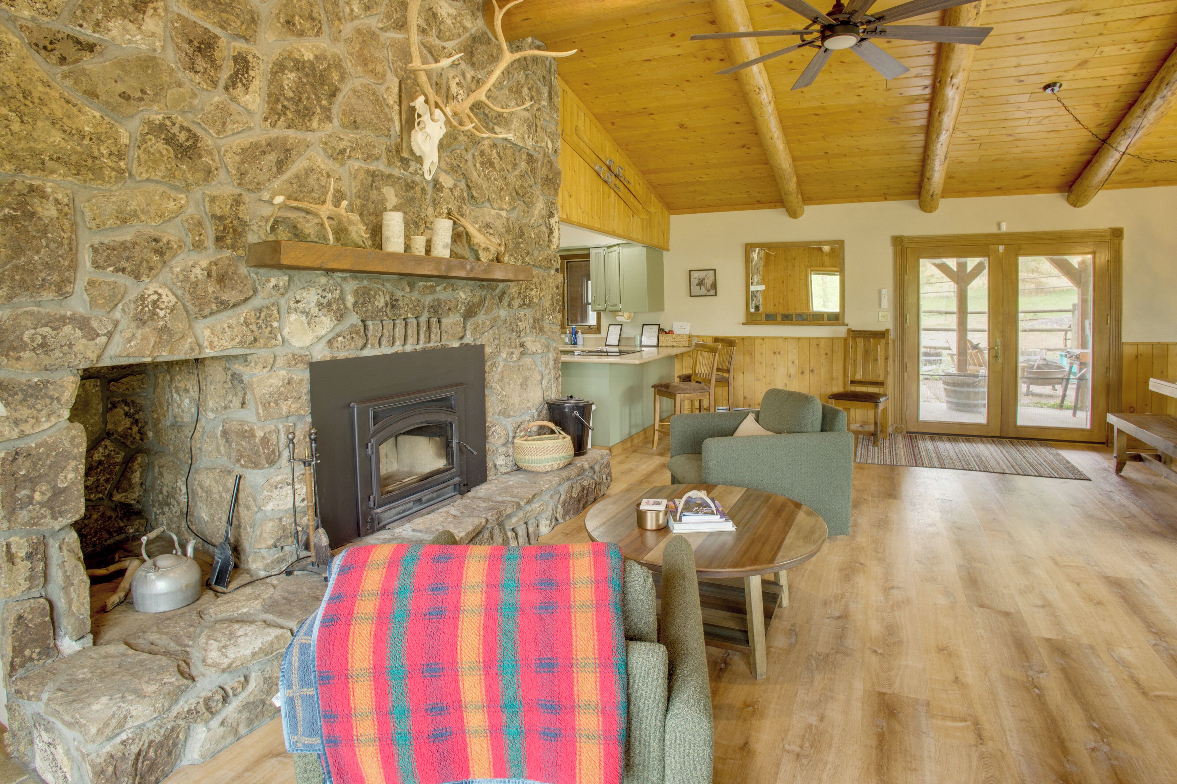 A stone fireplace, wooden ceiling, and a cozy seating area with a table and chairs.
