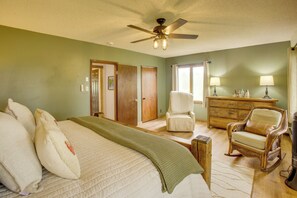 A bedroom with a bed, a chair, a dresser, and a ceiling fan. - Mountain Views + Bbqs: Updated Cody Cabin (Cody)