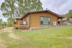 A log cabin with a deck, a large window, and a covered outdoor area. - Mountain Views + Bbqs: Updated Cody Cabin (Cody)