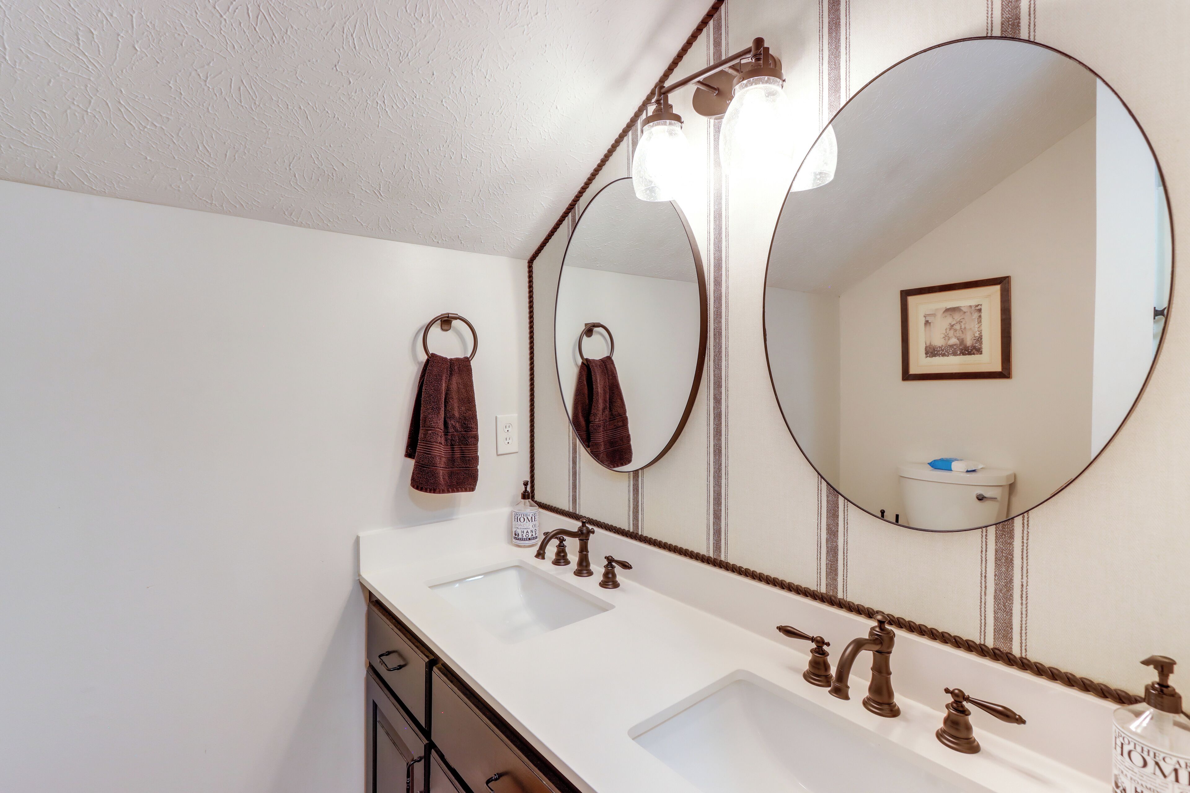 A bathroom with a large mirror, two sinks, and a towel rack.