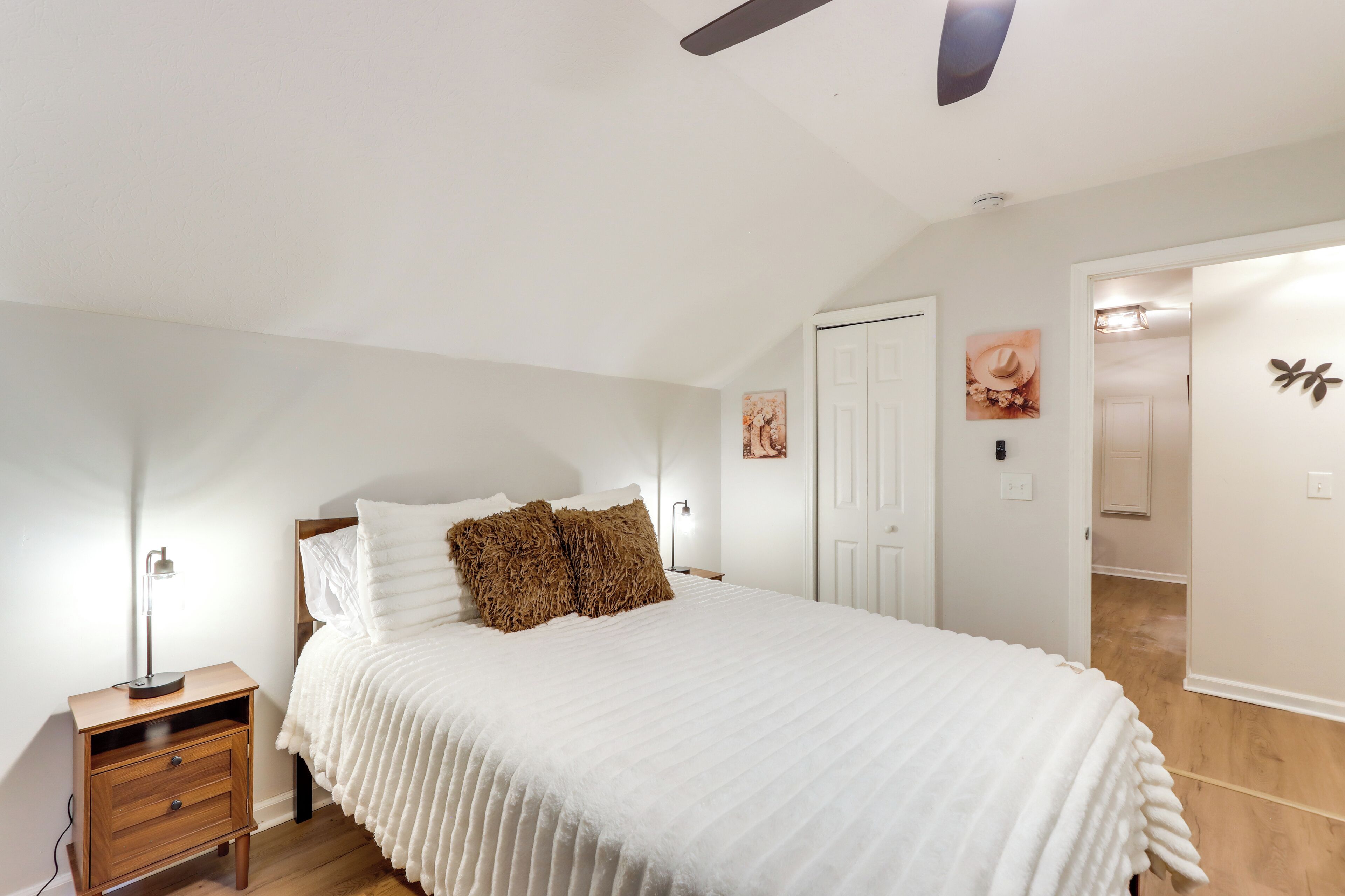 Une chambre à coucher avec un lit, une table de chevet, une lampe et un ventilateur de plafond.
