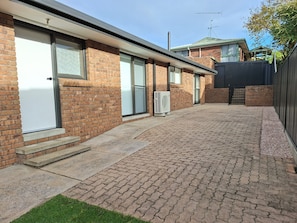 A brick building with a garage door, a paved driveway, and a small grassy area.