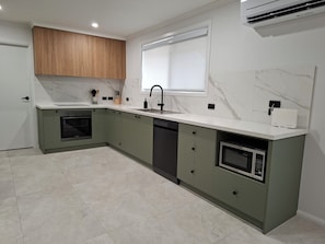 A kitchen with a built-in oven, a dishwasher, a microwave, and a sink with a faucet.