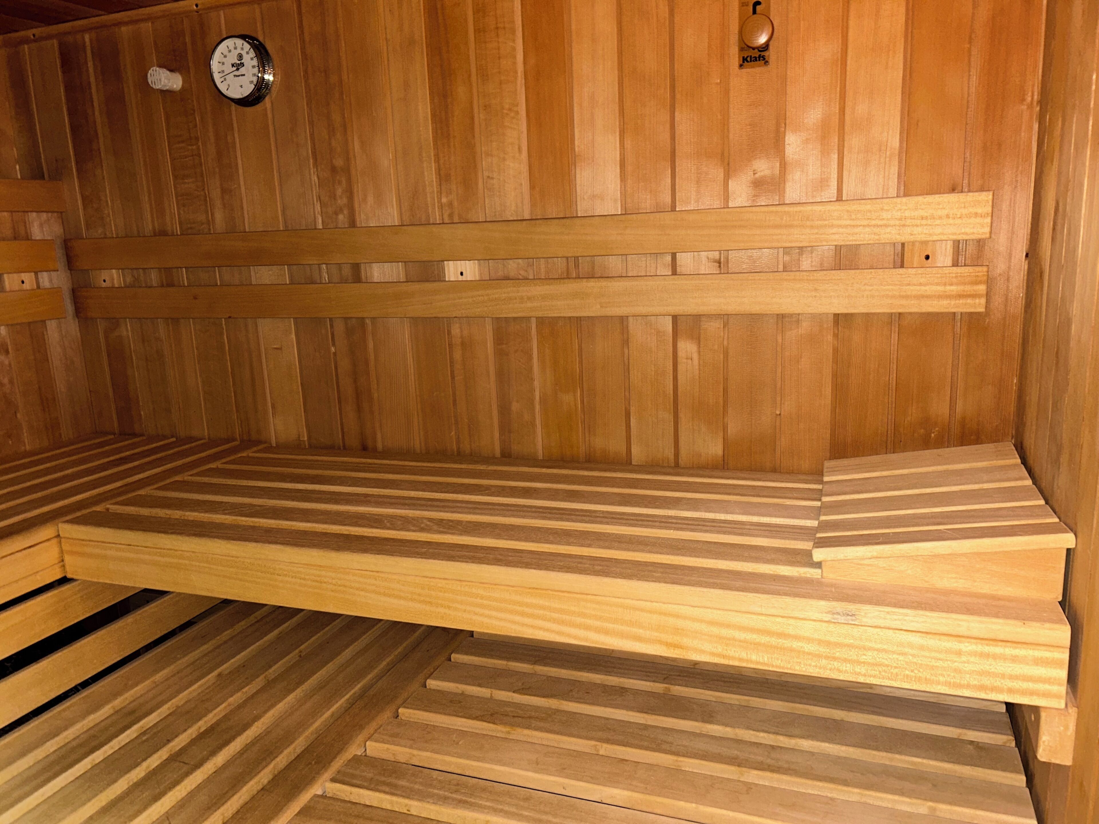 A wooden sauna with benches and a wall-mounted clock.