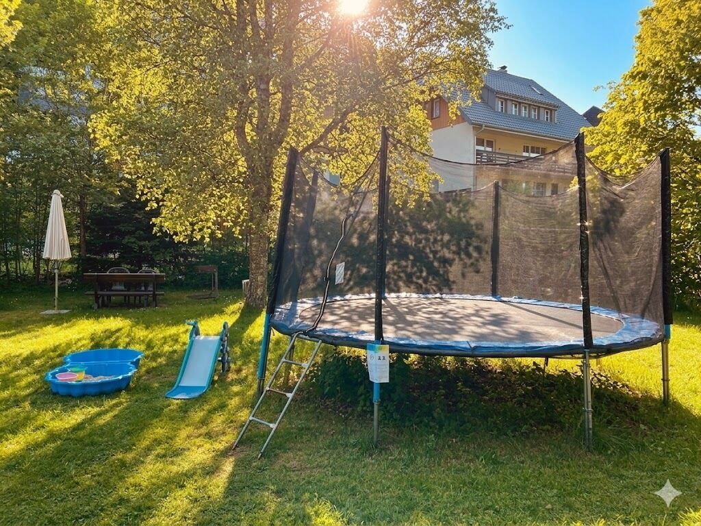 Un trampoline dans un jardin, avec une maison en arrière-plan.