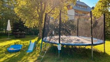 Un trampoline dans un jardin, avec une maison en arrière-plan.