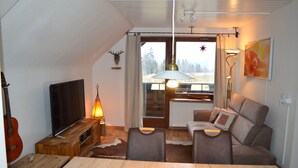 A cozy living room with a television, a guitar, a dining table, a sofa, and a fireplace. - Vacation home Albmatte-large garden-perfect for couples, groups and families (Sankt Blasien)