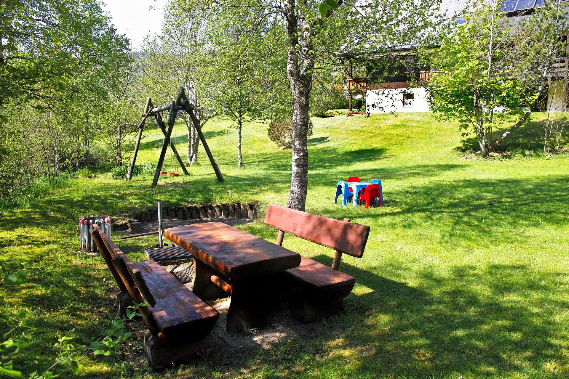A picnic area with a wooden bench, picnic table, and swings.