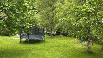 A trampoline surrounded by lush green trees in a backyard setting.