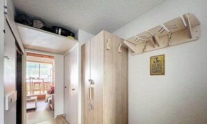 A hallway with a wooden wardrobe, a coat rack, and a sign indicating no ski boots inside. - Duplex 8 pers - ski à pied (Isola 2000)