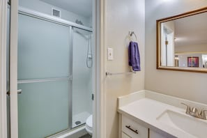 A bathroom with a glass shower enclosure, a white sink with a gold faucet, and a mirror with a gold frame. - Yuma Desert Oasis: Pool & Remote Work Setup! (Yuma)