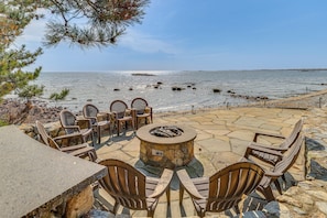 A patio with stone flooring, outdoor seating, and a fire pit. - Luxe 5,600-sq-ft Estate Waterfront + Pool (Westbrook)
