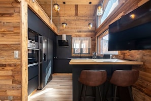 Eine moderne Küche mit Holzwänden, einer Bar mit Hockern und einem großen Fenster.