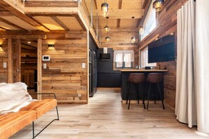 Un intérieur en bois comprenant un canapé, un coin cuisine avec un bar et un espace repas.