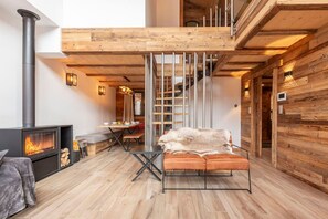 Un intérieur moderne agrémenté d’une cheminée, de poutres en bois, d’un escalier et d’un coin repas.