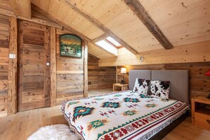 Une pièce chaleureuse, aménagée dans un chalet en bois, avec un lit, une table de chevet, une lampe et un panneau fixé au mur.