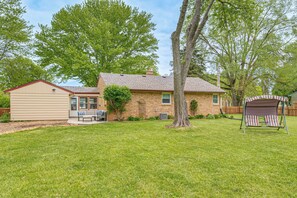 A house with a brick exterior, a covered porch, a swing set, and a small shed.