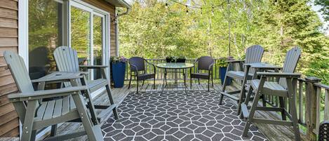 A covered patio with Adirondack chairs, a round table, and a patterned floor.