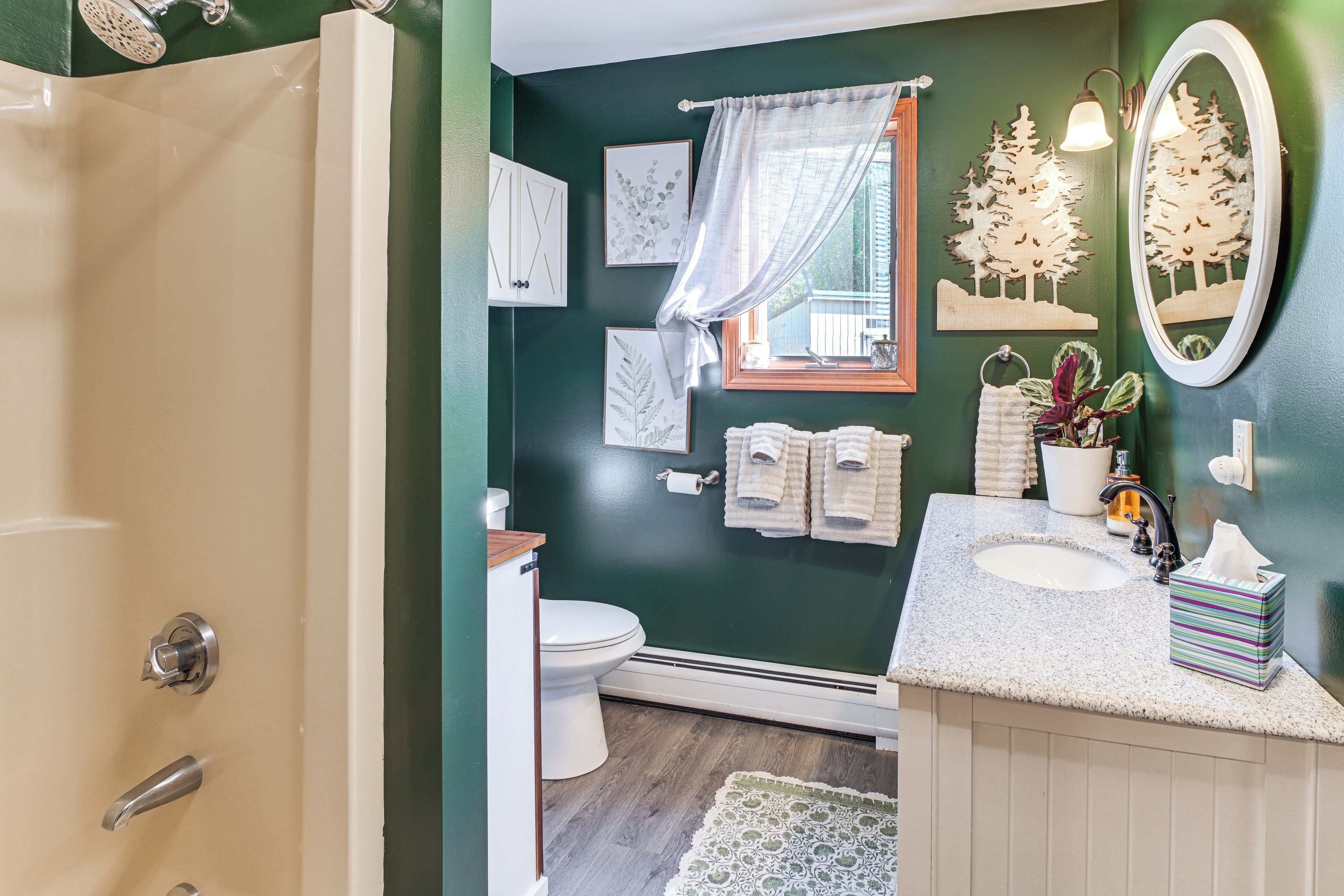 A bathroom with a shower, toilet, sink, and a mirror.
