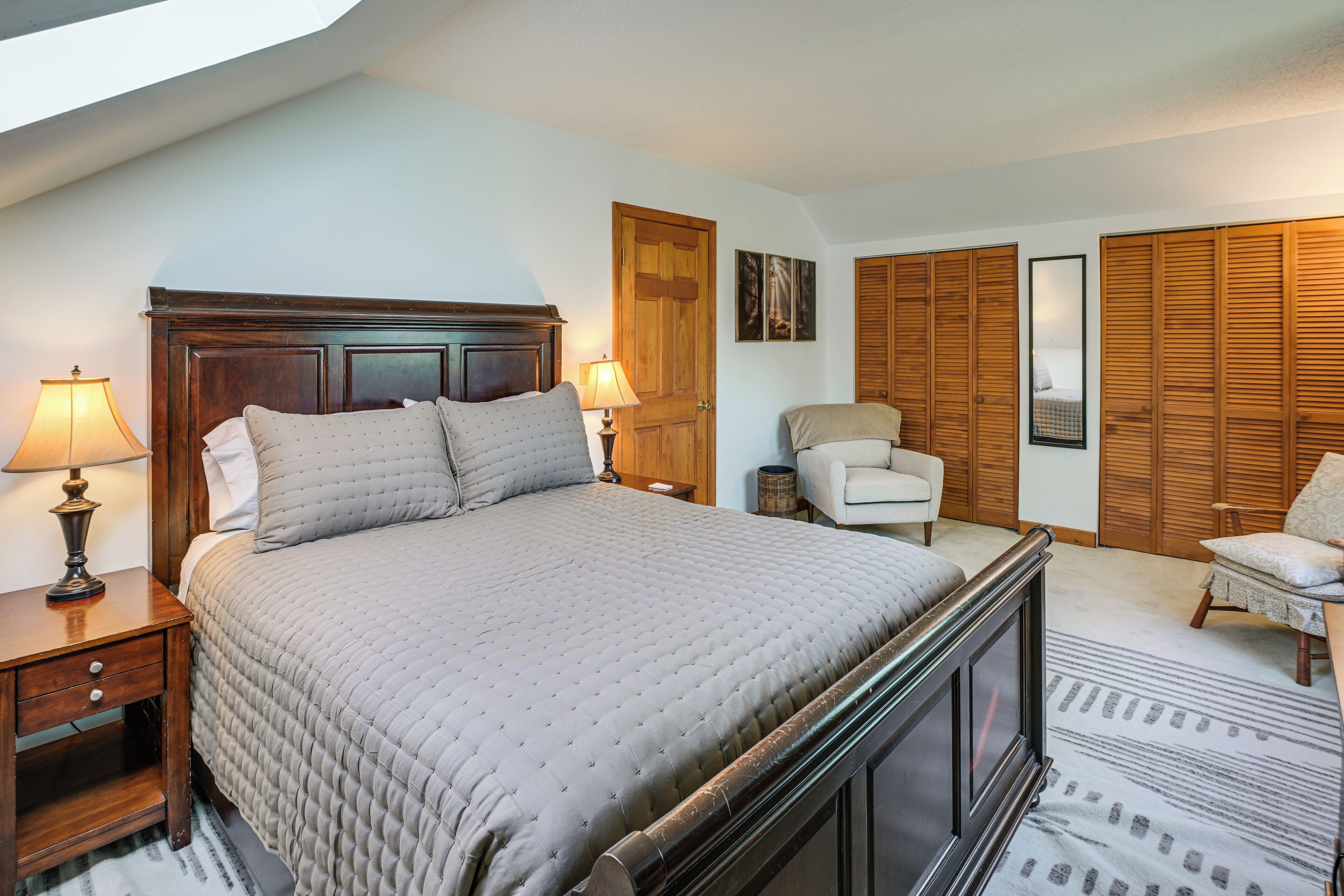 A bedroom with a large bed, two bedside tables with lamps, a chair, and a wardrobe.