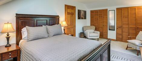 A bedroom with a large bed, two bedside tables with lamps, a chair, and a wardrobe.