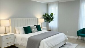 A modern bedroom with a bed, nightstands, a plant, and a green chair.