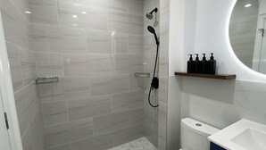 A modern bathroom with a shower, toilet, and sink.