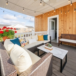 Een overdekt terras met een bank, kussens, een bijzettafeltje en lichtslingers.