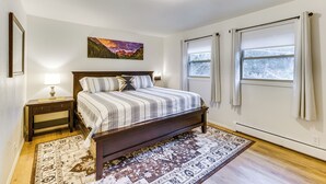 A bedroom with a bed, nightstand, lamp, windows, and a painting. - 10 Mi to The Incline! Gem w/ Game Room & Fire Pit (Green Mountain Falls)