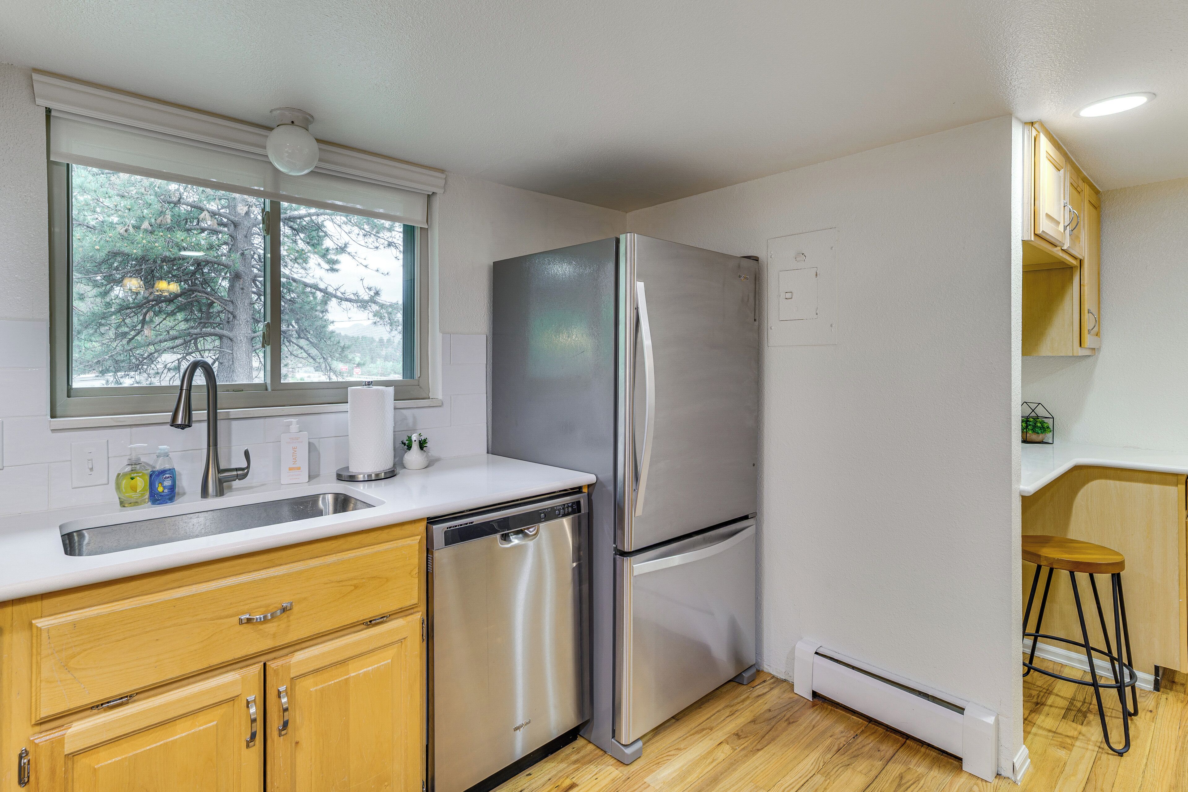 Una cocina con un refrigerador de acero inoxidable, lavavajillas, un lavabo y armarios de madera.