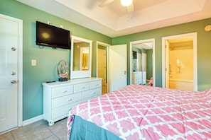 A bedroom with a bed, dresser, and a TV mounted on the wall.