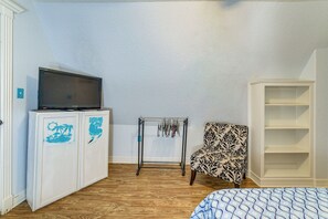 A room with a TV on a cabinet, a patterned chair, and a bookshelf. - Walk to Waves! Surfside Beach House w/ Ocean View (Freeport)
