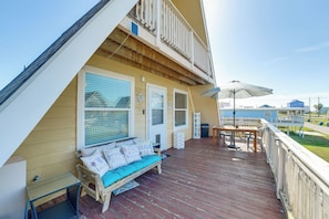 A deck with a wooden bench, a table, and a white railing. - Walk to Waves! Surfside Beach House w/ Ocean View (Freeport)