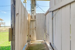 Un estrecho portón de madera que da a un edificio con una puerta metálica y un ventanal pequeño.