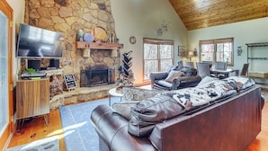 A cozy living room with a stone fireplace, leather sofa, and a flat-screen TV. - Private Hot Tub, Community Perks! Big Canoe Escape (Jasper)