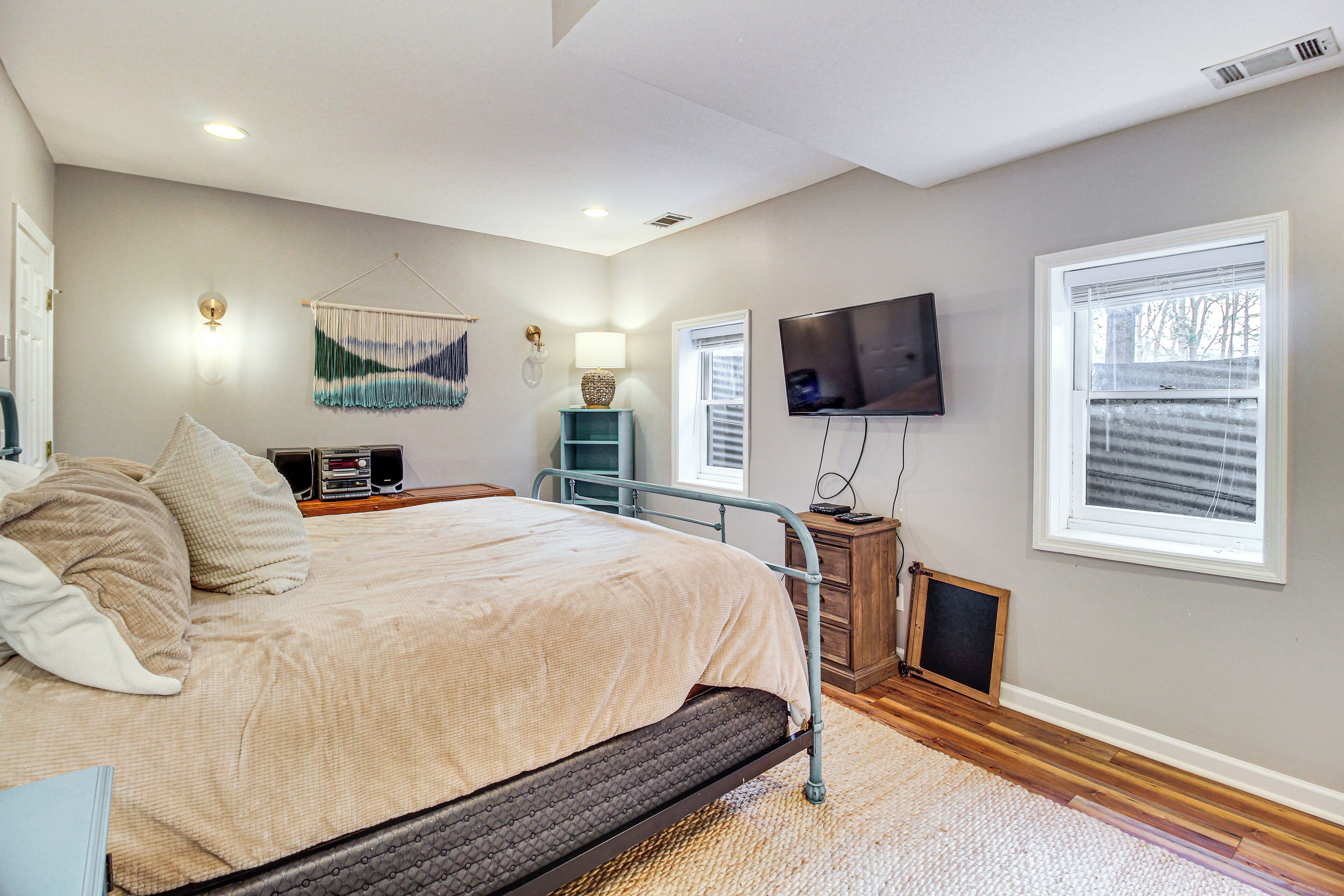 A bedroom with a bed, bedside tables, a TV, a wall-mounted lamp, and a window.