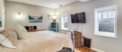 A bedroom with a bed, bedside tables, a TV, a wall-mounted lamp, and a window.