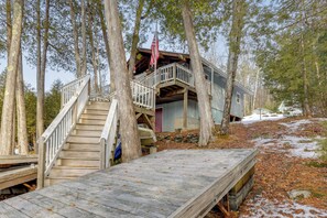 A cabin with a wooden deck, a staircase, and a porch. - Waterfront Deck + Views: Schroon Lake Sanctuary (Schroon Lake)