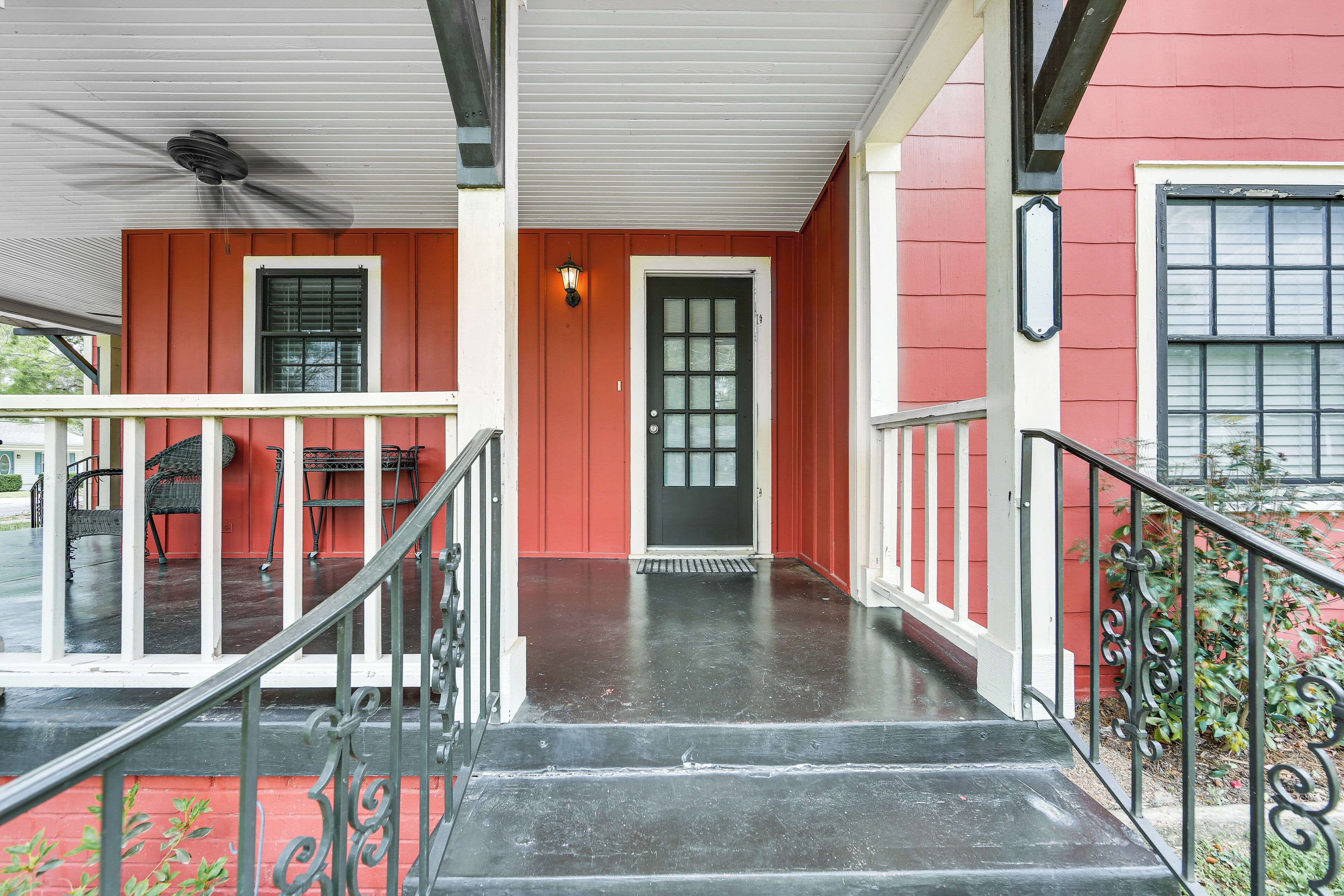 A red building with a black door, a covered porch, and a staircase leading to the entrance.