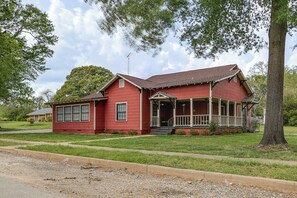 A red two-story house with a porch, a chimney, and a satellite dish.
