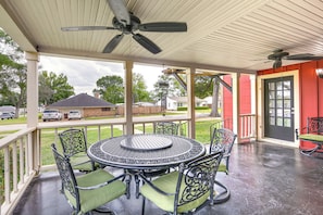 Eine überdachte Terrasse mit einem runden Tisch, Stühlen, einem Deckenventilator und Blick auf die Nachbarschaft.