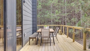 Terraza con mesa y sillas, con vista a un bosque.