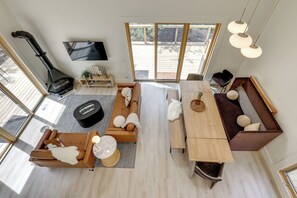 A modern living room with a fireplace, a TV, and a dining area with a wooden table and chairs.