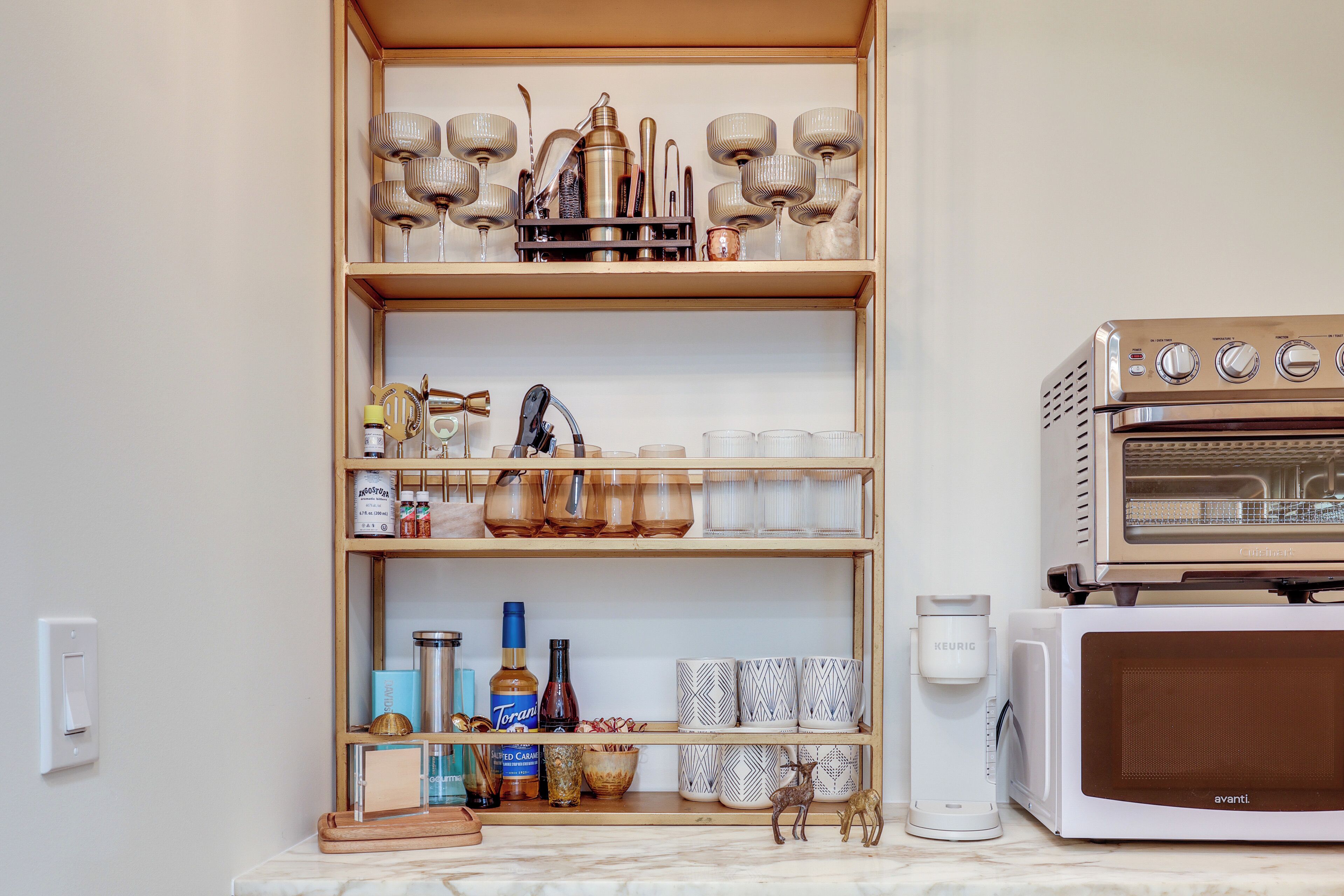 A kitchen with a built-in oven, a coffee maker, and shelves with kitchenware and decorative items.