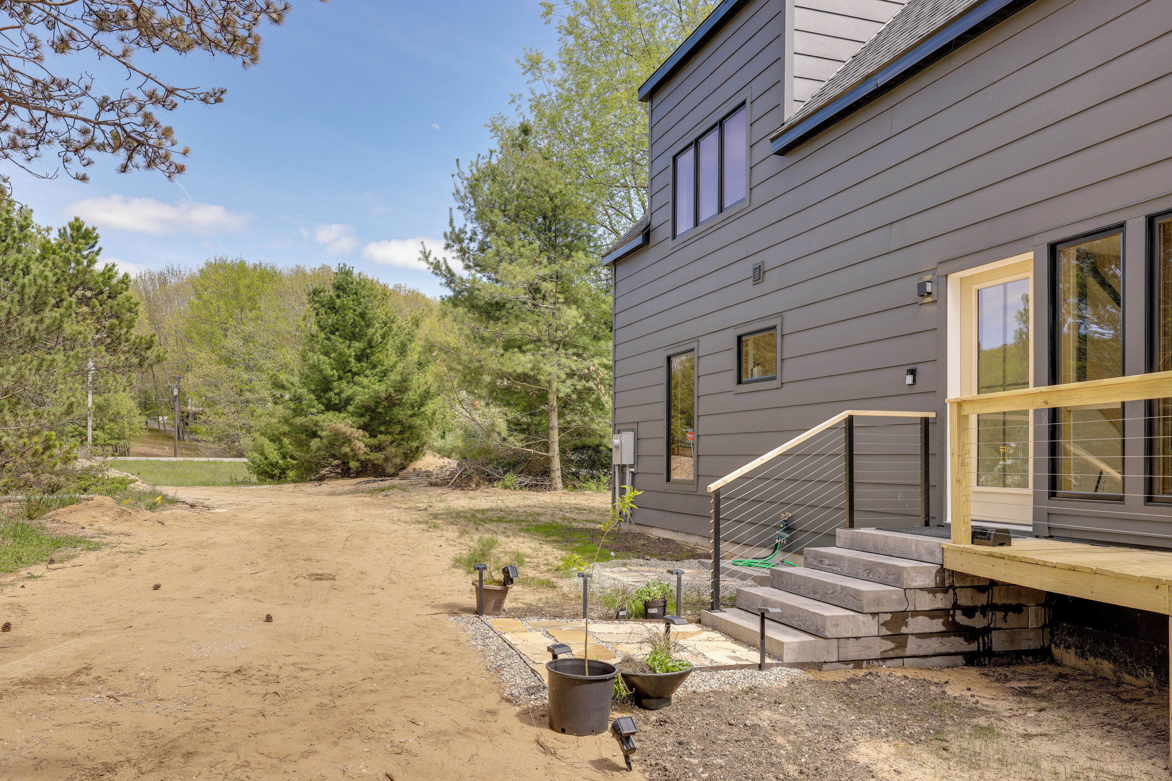 Una casa moderna con un patio cubierto, una escalera y un patio de tierra.