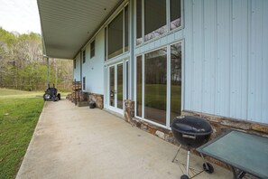 A house with a covered porch, a barbecue grill, and a table.