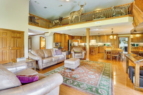 A spacious living room with leather sofas, a dining area, and a kitchen.