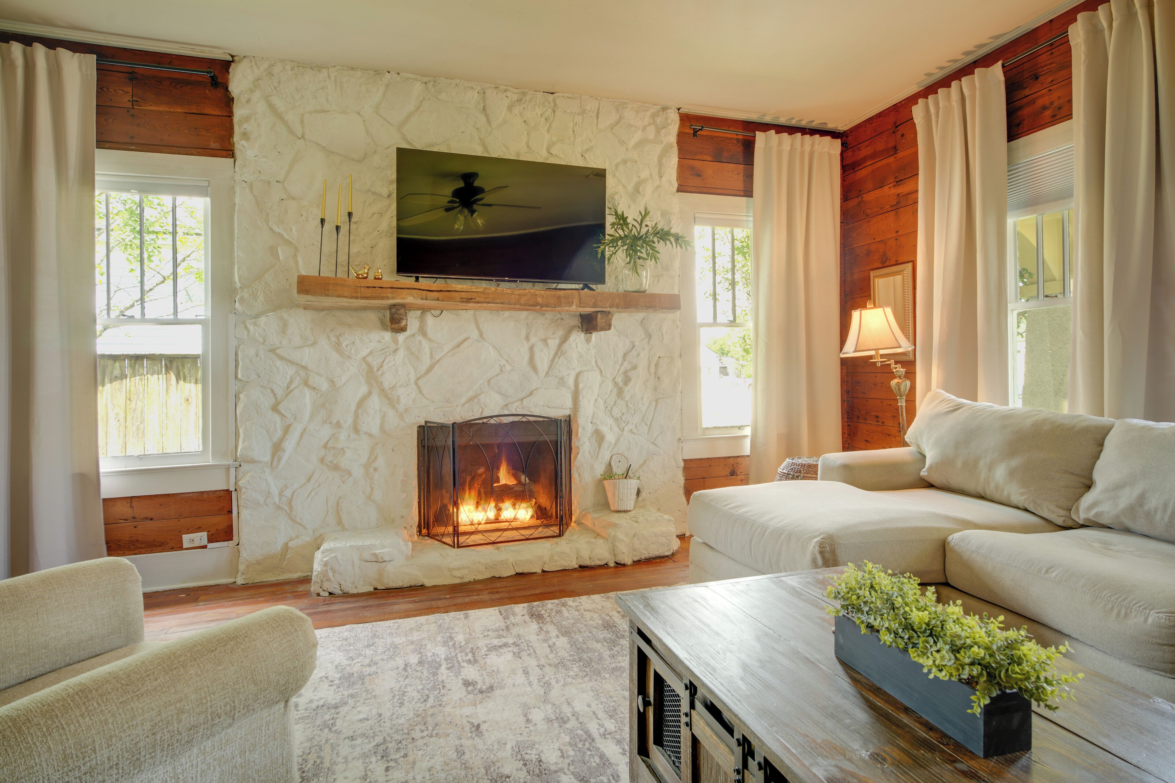 Una sala de estar con chimenea de piedra, un televisor montado encima y un sofá.